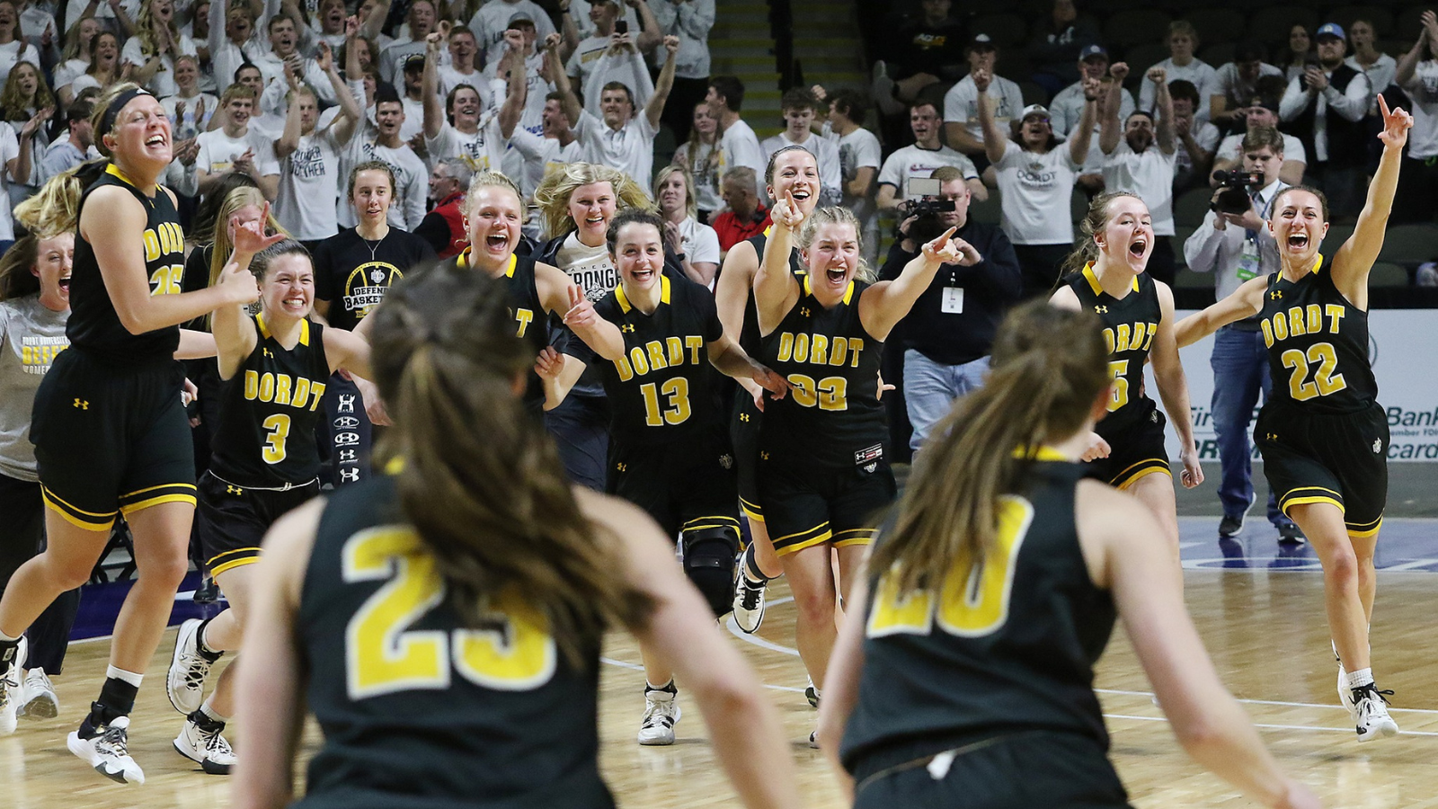 Dordt University’s women’s basketball team running towards each other in celebration.
