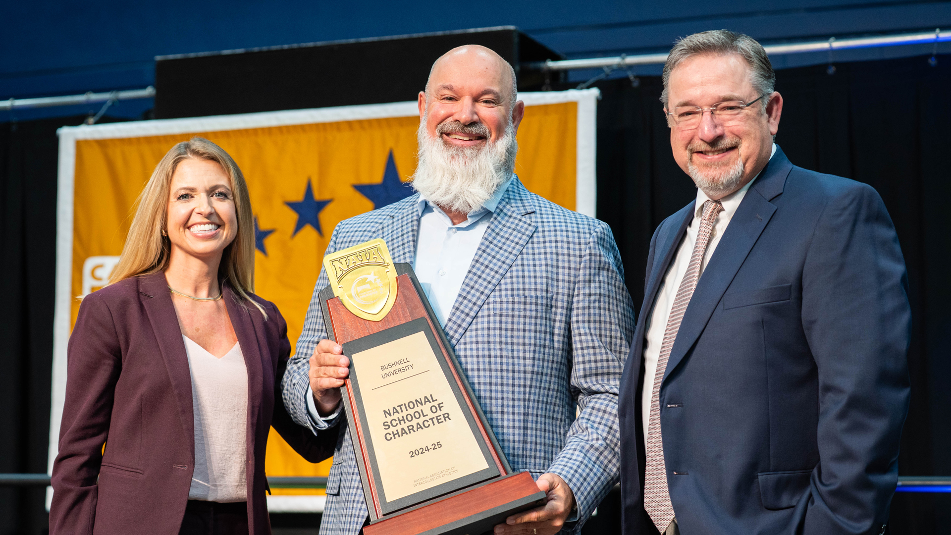 Two men and woman present National School of Character award to winning school Bushnell University